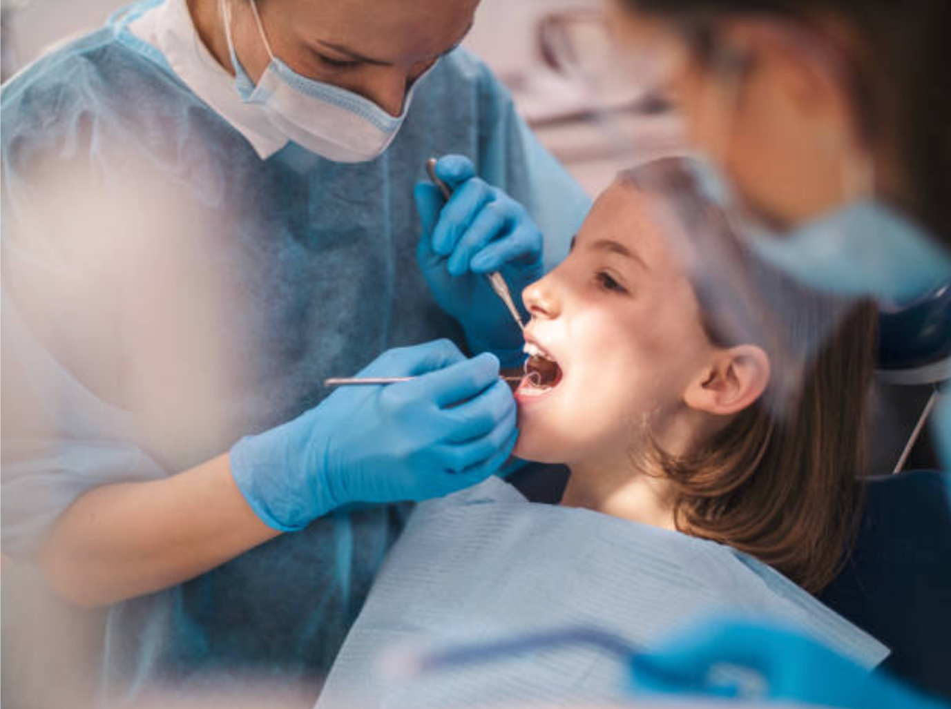 Dentist cleaning young girl's teeth